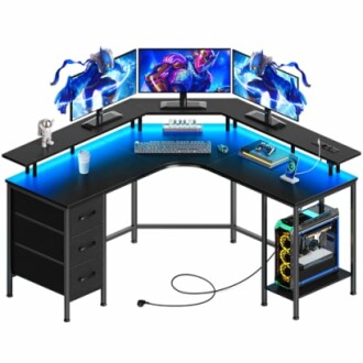 L-shaped gaming desk with triple monitors, LED lights, and gaming accessories.