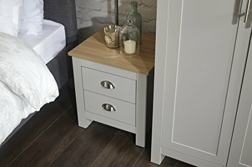 Modern nightstand with two drawers, candles, and glass bottles.