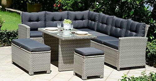 Outdoor rattan patio furniture set with a glass table, cushions, and greenery.